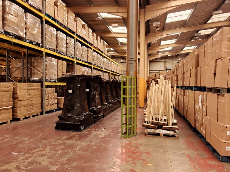 Assembled brooms stacked on pallets across the production floor