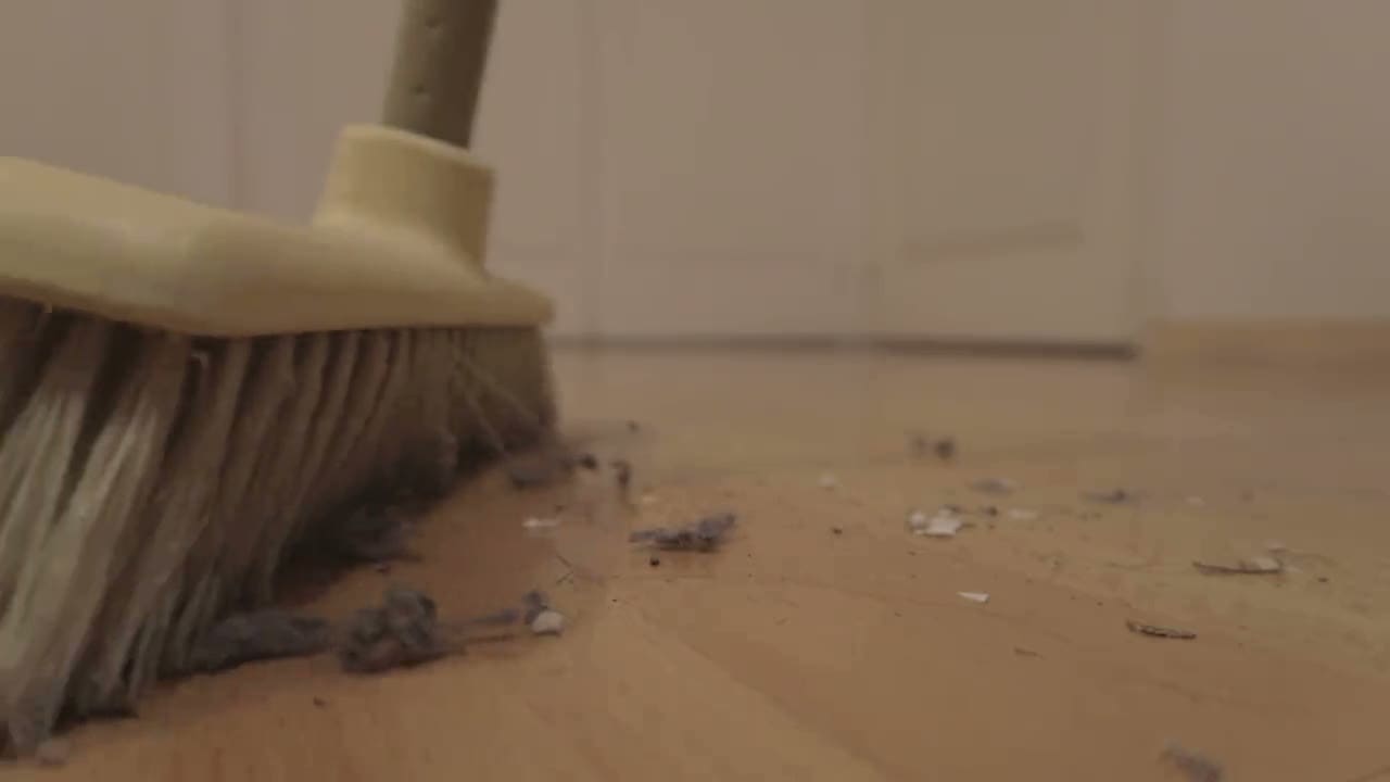 A broom sweeping debris across a hard floor